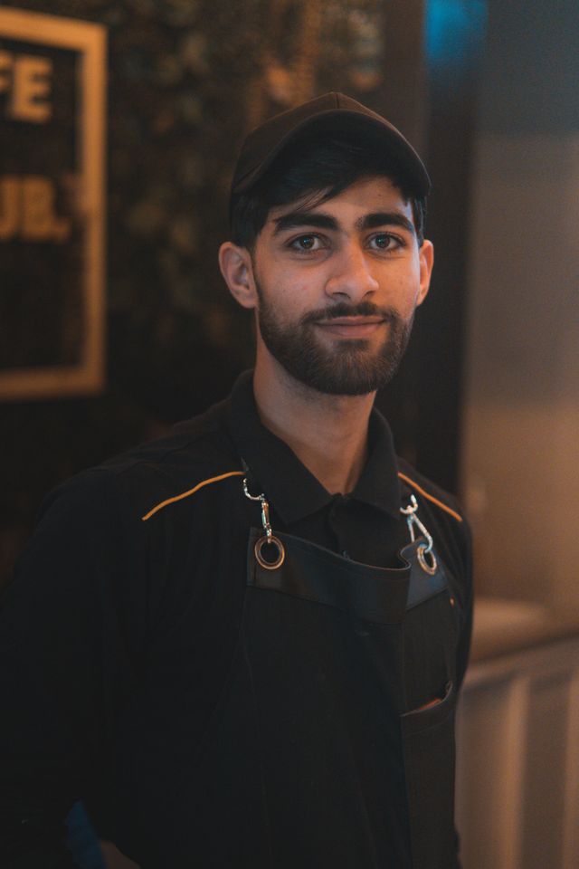 Fotografía de stock de un profesional de una cafetería con gorra y delantal.